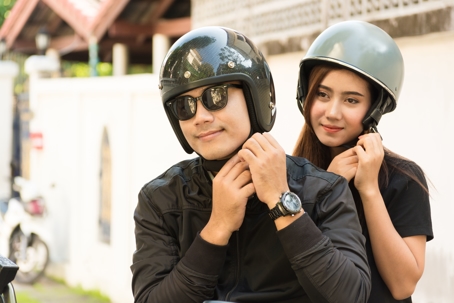 Two people wearing helmets on a motorcycle